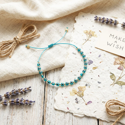 Turquoise beaded bracelet on a wooden surface with lavender and a 'Make a Wish' card.