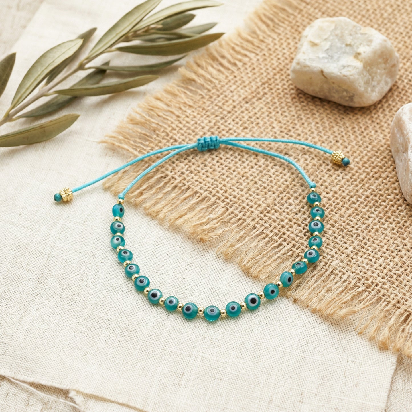 Turquoise beaded bracelet on a textured surface with stones and leaves