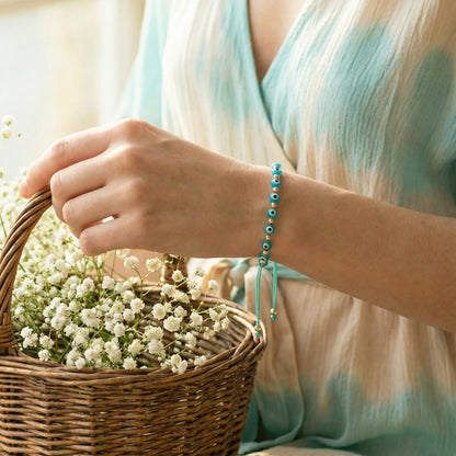 Person holding a basket of flowers wearing a turquoise bracelet