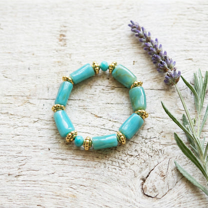 Turquoise beaded bracelet with gold accents on a wooden surface with lavender.