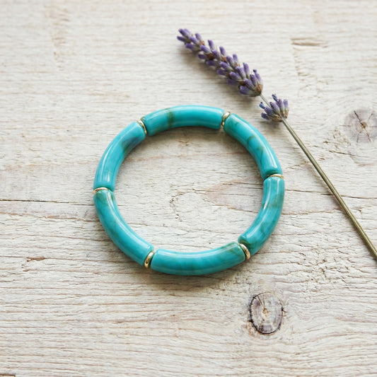 Turquoise bracelet on a wooden surface with lavender flowers