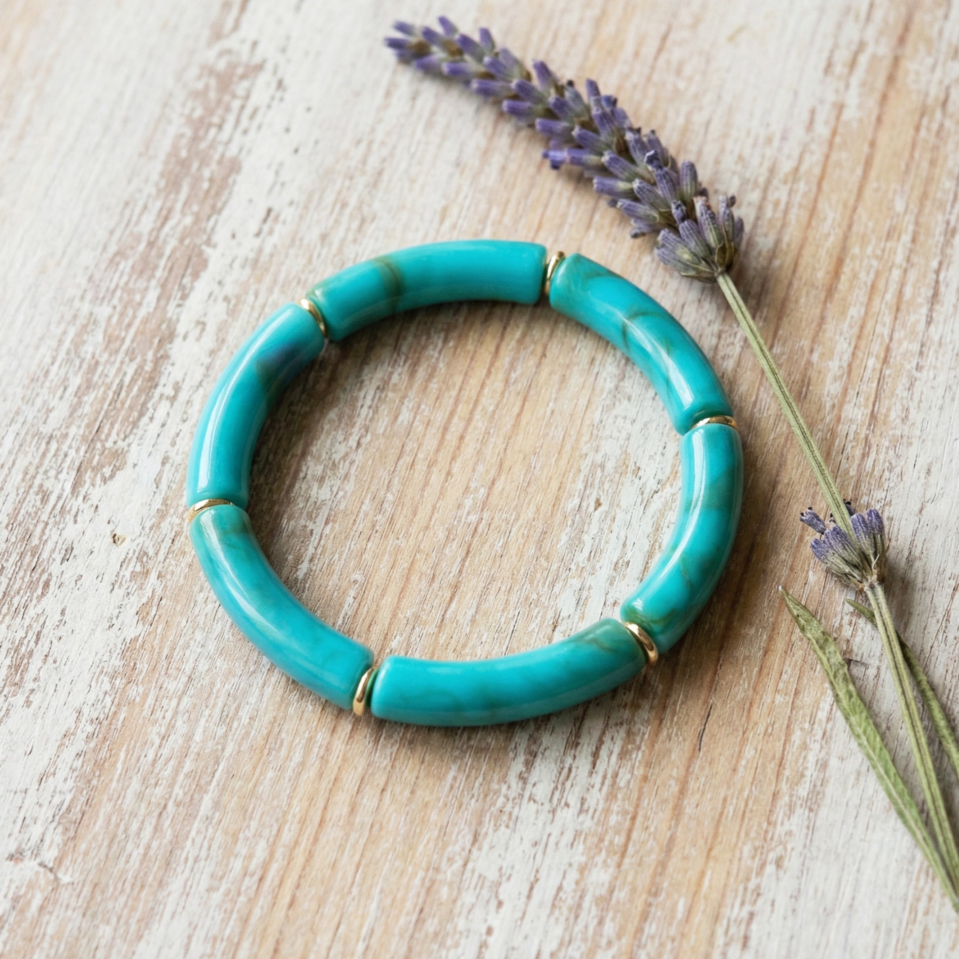 Turquoise bracelet on a wooden surface with lavender flowers