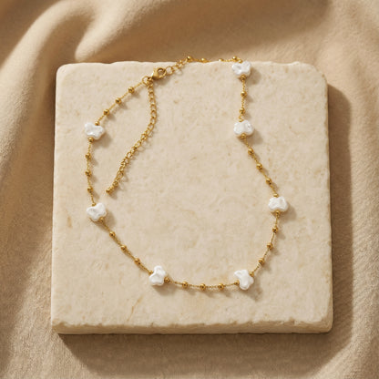 Gold necklace with white pearls on a beige stone surface