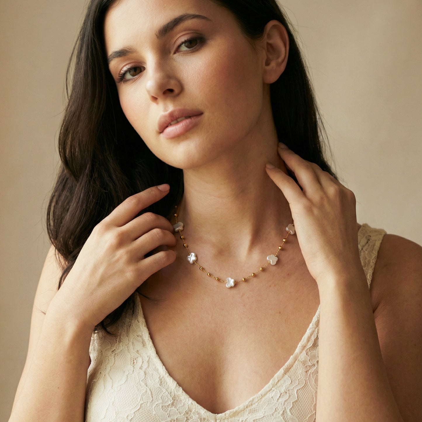 Woman wearing a delicate necklace against a neutral background