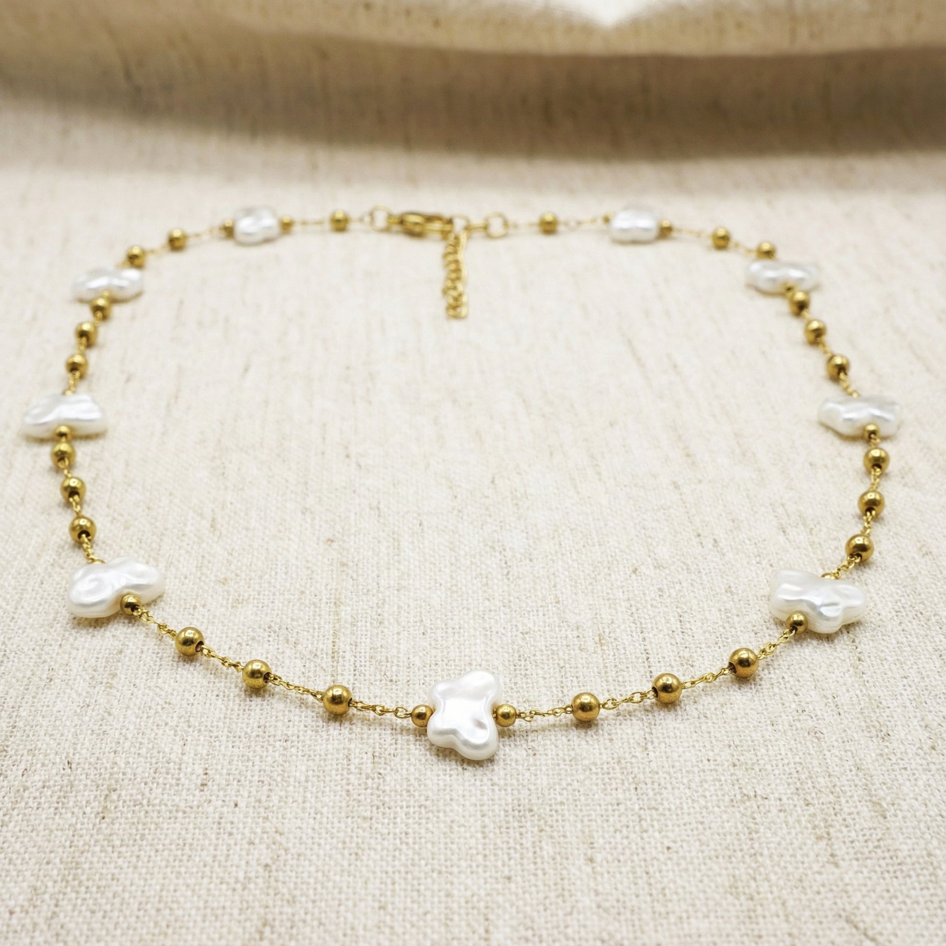 Gold bracelet with pearls on a beige fabric background