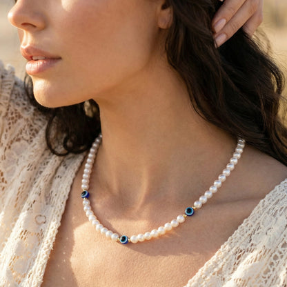 Pearl necklace with blue accents worn by a woman in a lace top.