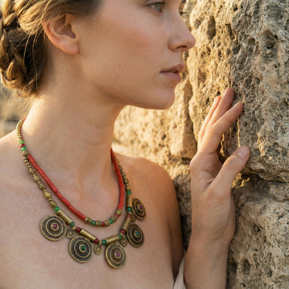 Woman wearing a decorative necklace against a stone wall