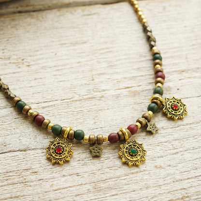 Decorative necklace with beads and gold pendants on a wooden surface
