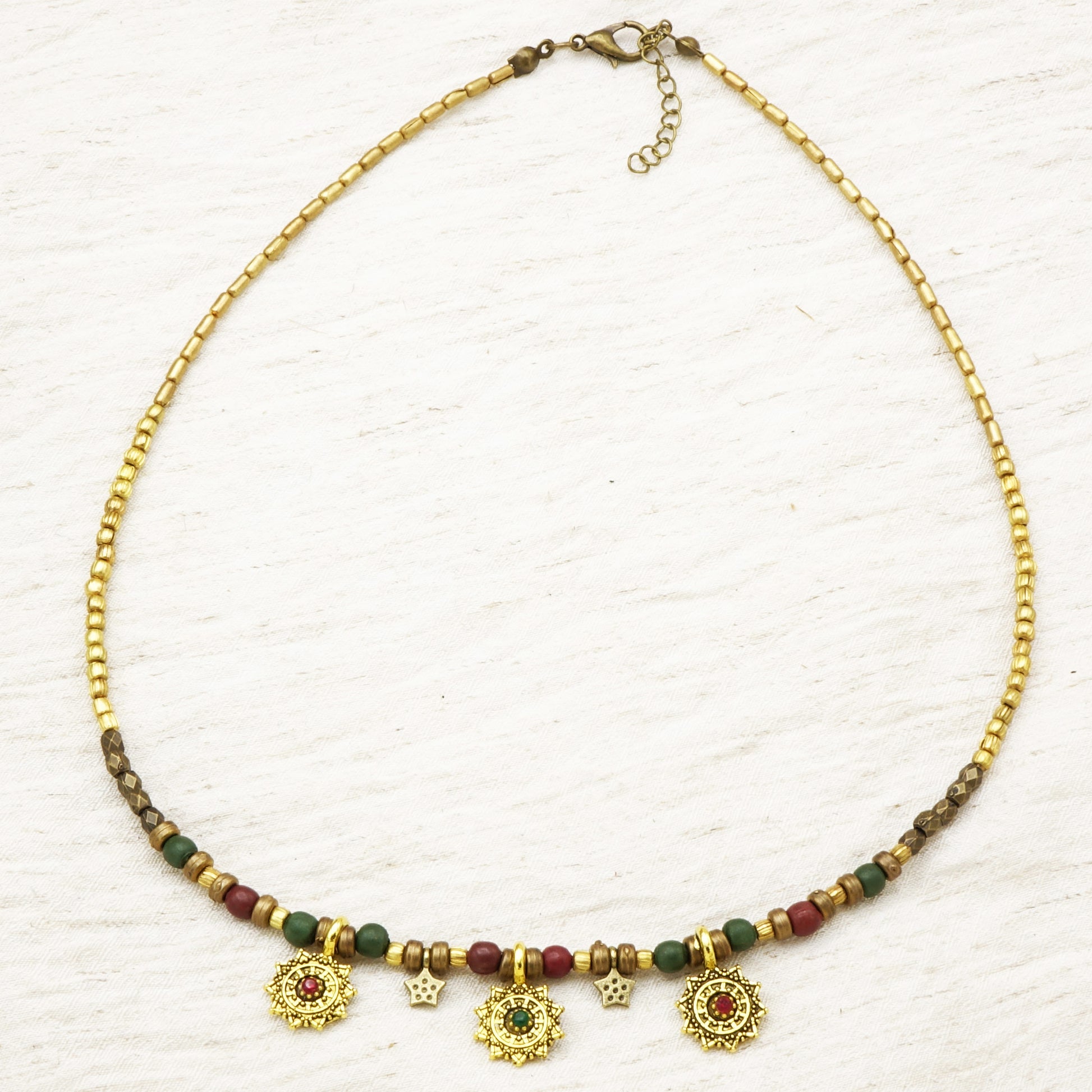 Necklace with gold chain, green and red beads on a white background