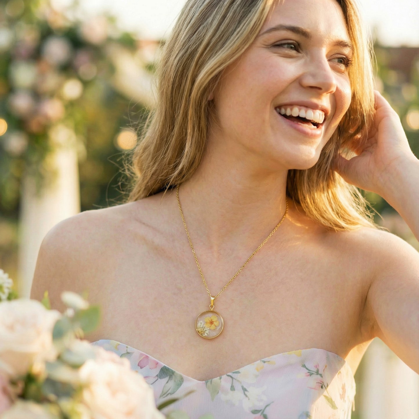 Woman wearing a gold necklace with a floral pendant outdoors
