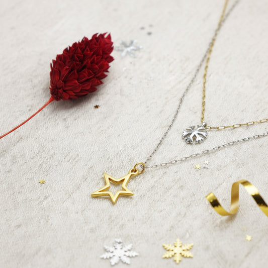 Gold star pendant necklace with a red flower on a light gray surface