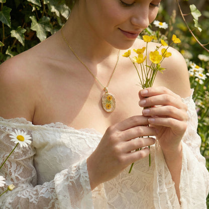 Woman holding yellow flowers wearing a necklace with a floral pendant in a natural setting