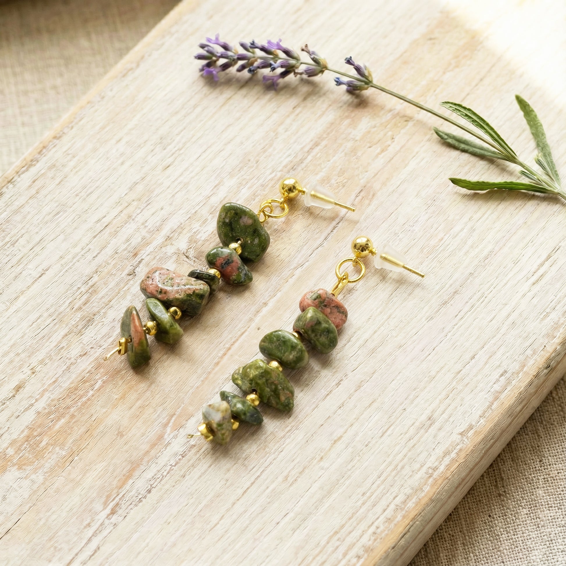 Green stone earrings on a wooden surface with lavender flowers
