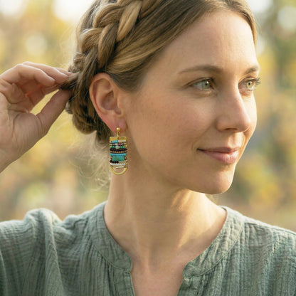 Woman wearing colorful earrings outdoors with blurred natural background