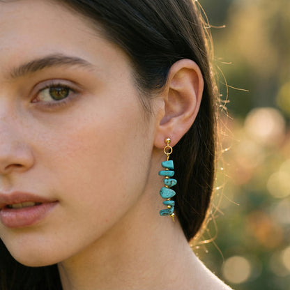 Close-up of a woman wearing turquoise earrings with a blurred natural background