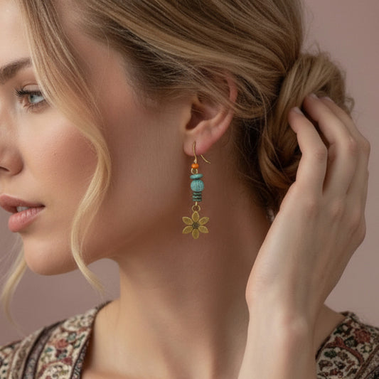 Woman wearing a floral earring with beads, adjusting her hair against a neutral background