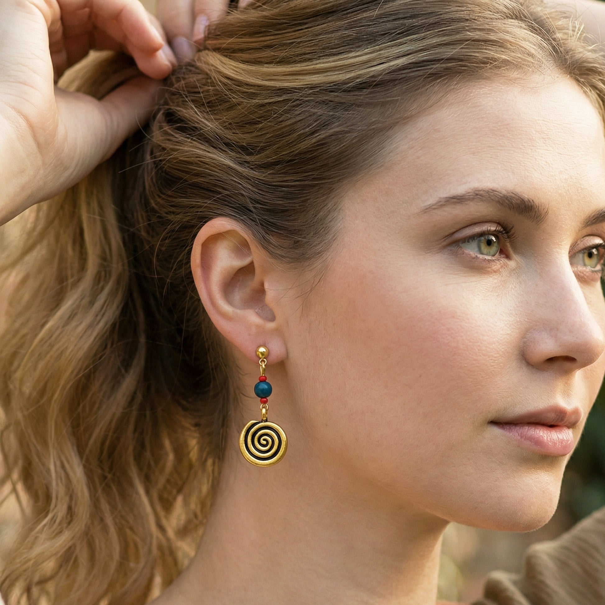 Close-up of a woman wearing spiral earrings with colored stones.
