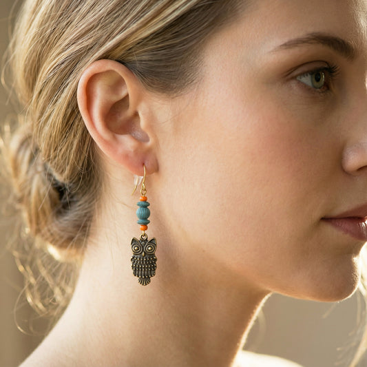 Close-up of a woman wearing an owl-shaped earring with beads.