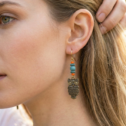 Close-up of a woman wearing an owl-shaped earring with beads.