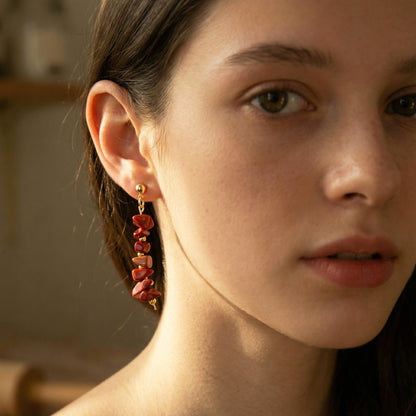 Close-up of a woman wearing red heart-shaped earrings with a blurred background
